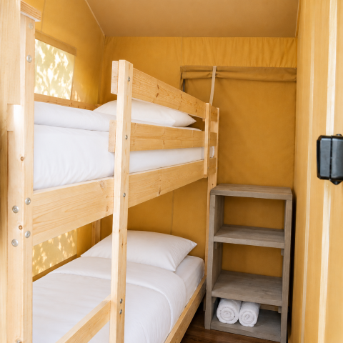 Vista interna della tenda safari Comfort al Camping 't Veld, Olanda, con letti a castello e scaffale.