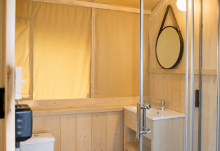 Bagno nella tenda safari Comfort al Camping 't Veld nei Paesi Bassi con pannelli in legno e doccia moderna.