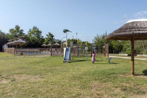 Children playing on a playground with a slide at Seasonova Camping Le Plan d’Eau holiday park, Nouvelle-Aquitaine, France.