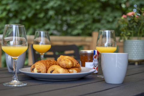 Petit-déjeuner en plein air avec croissants, jus d’orange, café et confiture à Seasonova Camping Le Plan d’Eau.