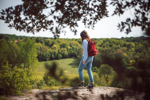 Eine Person mit rotem Rucksack wandert durch die Natur bei Saint Yrieix sur Charente in Nouvelle-Aquitaine, Frankreich.
