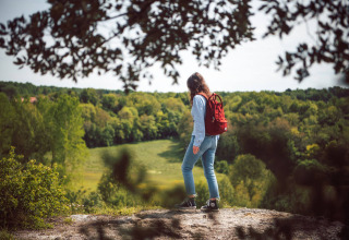 A person with a red backpack explores a scenic overlook near Saint Yrieix sur Charente, Nouvelle-Aquitaine, France.