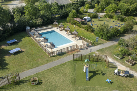 Aerial view of pool, playground and grassy spaces at Seasonova Camping Le Plan d’Eau, Nouvelle-Aquitaine, France.