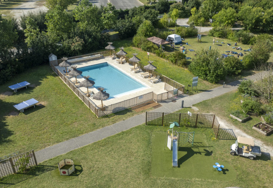 Aerial view of pool, playground and grassy spaces at Seasonova Camping Le Plan d’Eau, Nouvelle-Aquitaine, France.
