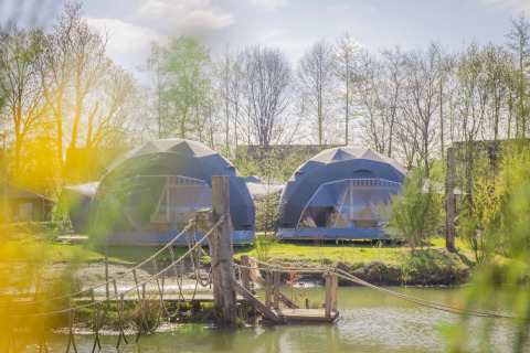 Dos tiendas Holly redondas en Holiday Park Sallandshoeve, Países Bajos, con puente colgante y lago.