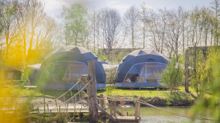 Twee ronde Holly-tenten bij vakantiepark Sallandshoeve in Nederland, met een hangbrug over het water.