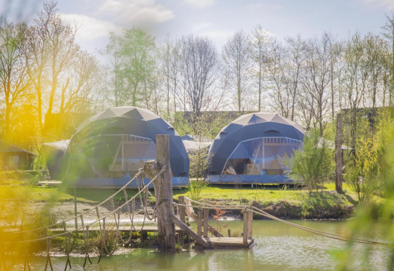 Twee ronde Holly-tenten bij vakantiepark Sallandshoeve in Nederland, met een hangbrug over het water.