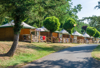 Alignement de cabanes en bois avec terrasses à Seasonova Camping Le Val de Coise, Pays de la Loire, France.