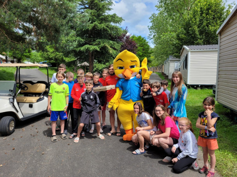 Niños y adultos posan con una mascota amarilla en Seasonova Camping Le Val de Coise, en Países del Loira, Francia.