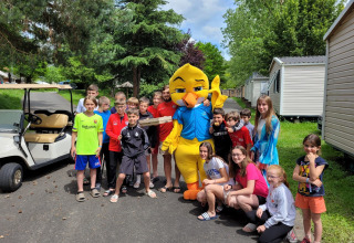Kinder und Erwachsene posieren mit einem gelben Maskottchen im Seasonova Camping Le Val de Coise, Frankreich.