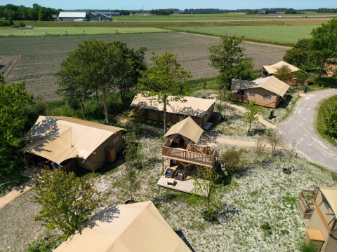 Vista aérea de la tienda Safari 2 en Lauwersmeer, Países Bajos, rodeada de árboles y campos tranquilos.