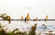 Windsurfer si godono l’acqua nel parco vacanze Lauwersmeer a Groningen, Paesi Bassi, in una giornata nuvolosa.