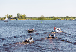 Varias embarcaciones navegan por un lago cerca de Vierhuizen, Groningen, Países Bajos, con campos verdes al fondo.