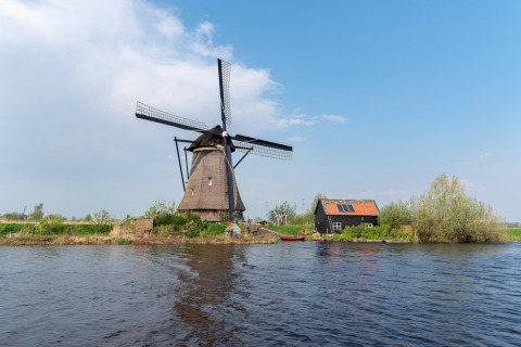 Molino de viento tradicional junto al agua cerca de Vierhuizen, Groningen, Países Bajos, en un día soleado.