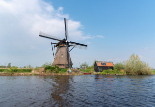 Tradizionale mulino a vento olandese vicino all'acqua presso Vierhuizen, Groningen, in una giornata soleggiata.