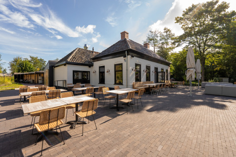 Zona de comedor al aire libre en Lauwersmeer, un parque vacacional en Groningen, Países Bajos, con mesas y sillas.