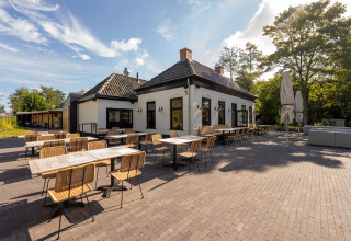Area pranzo esterna presso il parco vacanze Lauwersmeer a Groningen, Paesi Bassi, con tavoli e sedie.
