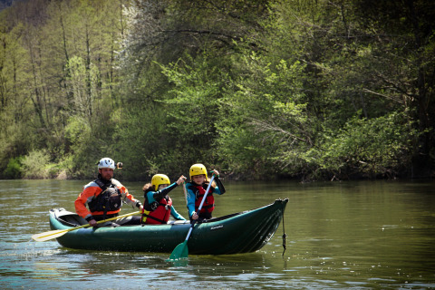 Trois personnes pagaient en canoë sur une rivière calme près de Saint Geniez d'Olt, en Occitanie, France.