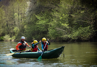 Tre persone fanno canoa su un fiume tranquillo vicino a Saint Geniez d'Olt, in Occitania, Francia.