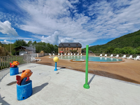Piscine extérieure et aire de jeux aquatique au Seasonova Camping Les Rives d'Olt et Aubrac en Occitanie, France.