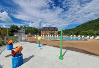 Piscina all'aperto e area giochi d'acqua al Seasonova Camping Les Rives d'Olt et Aubrac in Occitania, Francia.