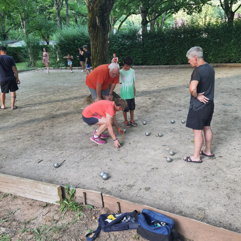 Persone che giocano a pétanque su un campo sabbioso a Seasonova Camping Les Rives d'Olt et Aubrac, Occitania, Francia.