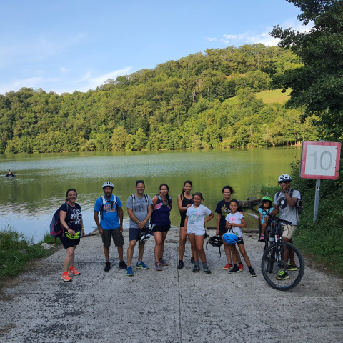 Un groupe de personnes avec des vélos et des sacs à dos près d’un lac au Seasonova Camping Les Rives d'Olt et Aubrac en Occitanie.