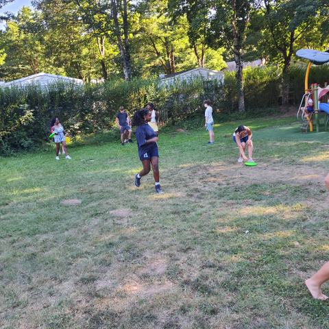 Bambini giocano e corrono sul prato al villaggio vacanze Seasonova Camping Les Rives d'Olt et Aubrac in Occitania, Francia.