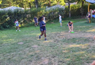 Kinder spielen und rennen auf einer Wiese im Ferienpark Seasonova Camping Les Rives d'Olt et Aubrac, Occitanie.