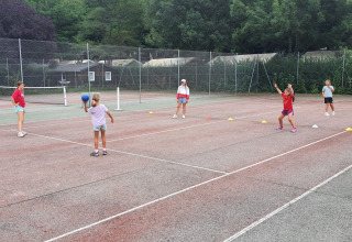 Des enfants jouent à un jeu de ballon sur un court de tennis au Camping Les Rives d'Olt et Aubrac en Occitanie.