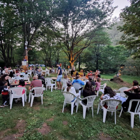 Concert en plein air dans un camping d’Occitanie, France, avec public installé sur des chaises blanches en plastique.