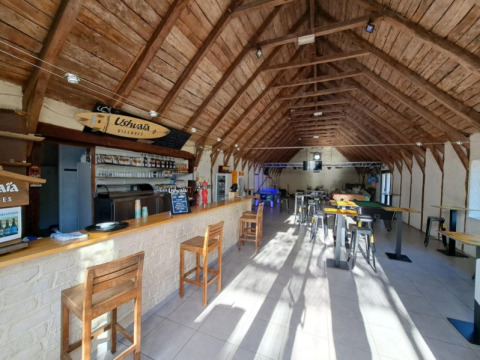 Foto interna di un bar con travi in legno al Seasonova Camping Les Rives d'Olt et Aubrac in Occitania, Francia.