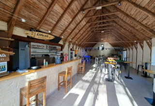Foto interna di un bar con travi in legno al Seasonova Camping Les Rives d'Olt et Aubrac in Occitania, Francia.
