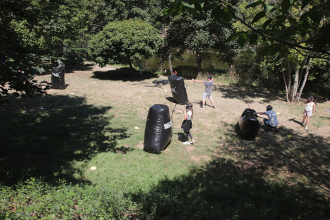 Des enfants et adultes jouent à l'archery tag en plein air au Seasonova Camping Les Rives d'Olt, en France.