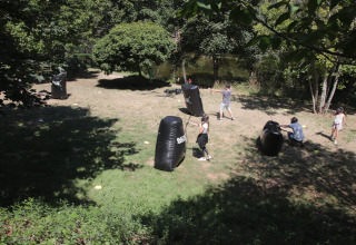 Des enfants et adultes jouent à l'archery tag en plein air au Seasonova Camping Les Rives d'Olt, en France.
