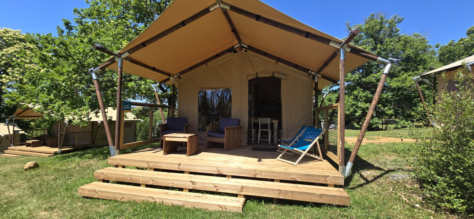 Houten terras van Slow Lodge safaritent met buitenzitje en toegang tot de eethoek in het tentinterieur.