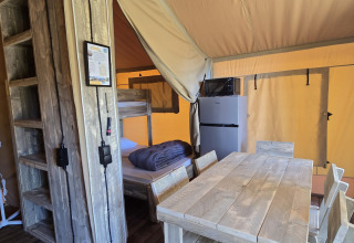 Interno della tenda safari 'Slow Lodge' al Camping Seasonova Lac de Bournazel con area pranzo e cucina.
