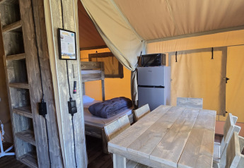 Interno della tenda safari 'Slow Lodge' al Camping Seasonova Lac de Bournazel con area pranzo e cucina.