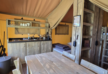 Interieur van de safaritent Slow Lodge op Camping Seasonova Lac de Bournazel in Frankrijk met keuken en stapelbedden.
