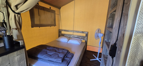 Interno tenda safari allo Slow Lodge, Camping Seasonova Lac de Bournazel, Francia, con letto e ventilatore.
