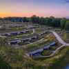 Holiday park in Gulpen, Limburg, Netherlands, featuring modern lodges nestled in green hills at sunset.