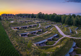 Vakantiepark in Gulpen, Limburg, Nederland, met moderne lodges in groene heuvels bij zonsondergang.
