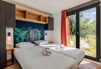 Moderne lodgekamer Green Valley 6 in Gulpen, Nederland, met twee bedden en uitzicht op de natuur.