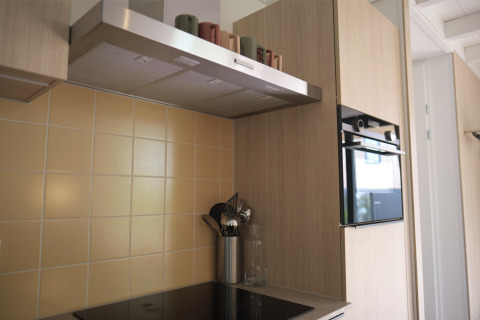 Cocina moderna con placa de cerámica, horno, campana extractora y azulejos beige en Woodland Lodge 6, Gulpen.