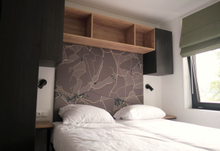 Moderne slaapkamer met kaart-hoofdbord, opbergvakken en raam in Woodland Lodge 6, Gulpen, Nederland.