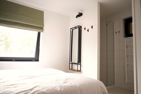 Dormitorio moderno y área de ducha en Woodland Lodge 6 en Gulpen, Países Bajos, con decoración minimalista.