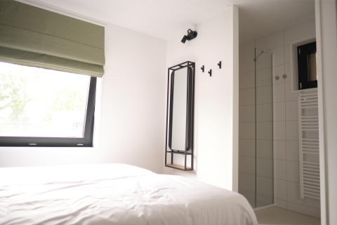 Modernes Schlafzimmer und Dusche in der Woodland Lodge 6 in Gulpen, Niederlande, minimalistisch gestaltet.