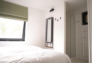 Moderne slaapkamer en douche in Woodland Lodge 6 in Gulpen, Nederland, met een minimalistisch ontwerp.