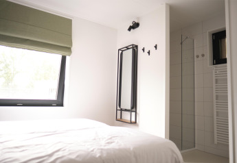 Modernes Schlafzimmer und Dusche in der Woodland Lodge 6 in Gulpen, Niederlande, minimalistisch gestaltet.