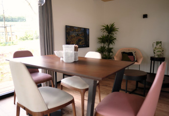 Essbereich mit Holztisch, modernen Stühlen und Pflanzen in Timber Lodge 4, Gulpen, Niederlande.